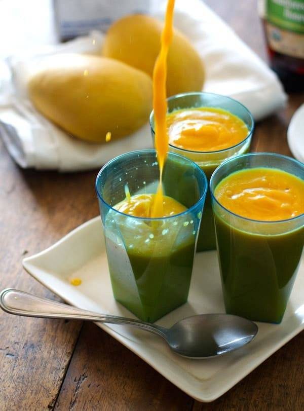 Three papaya mango smoothies pouring in a cup.