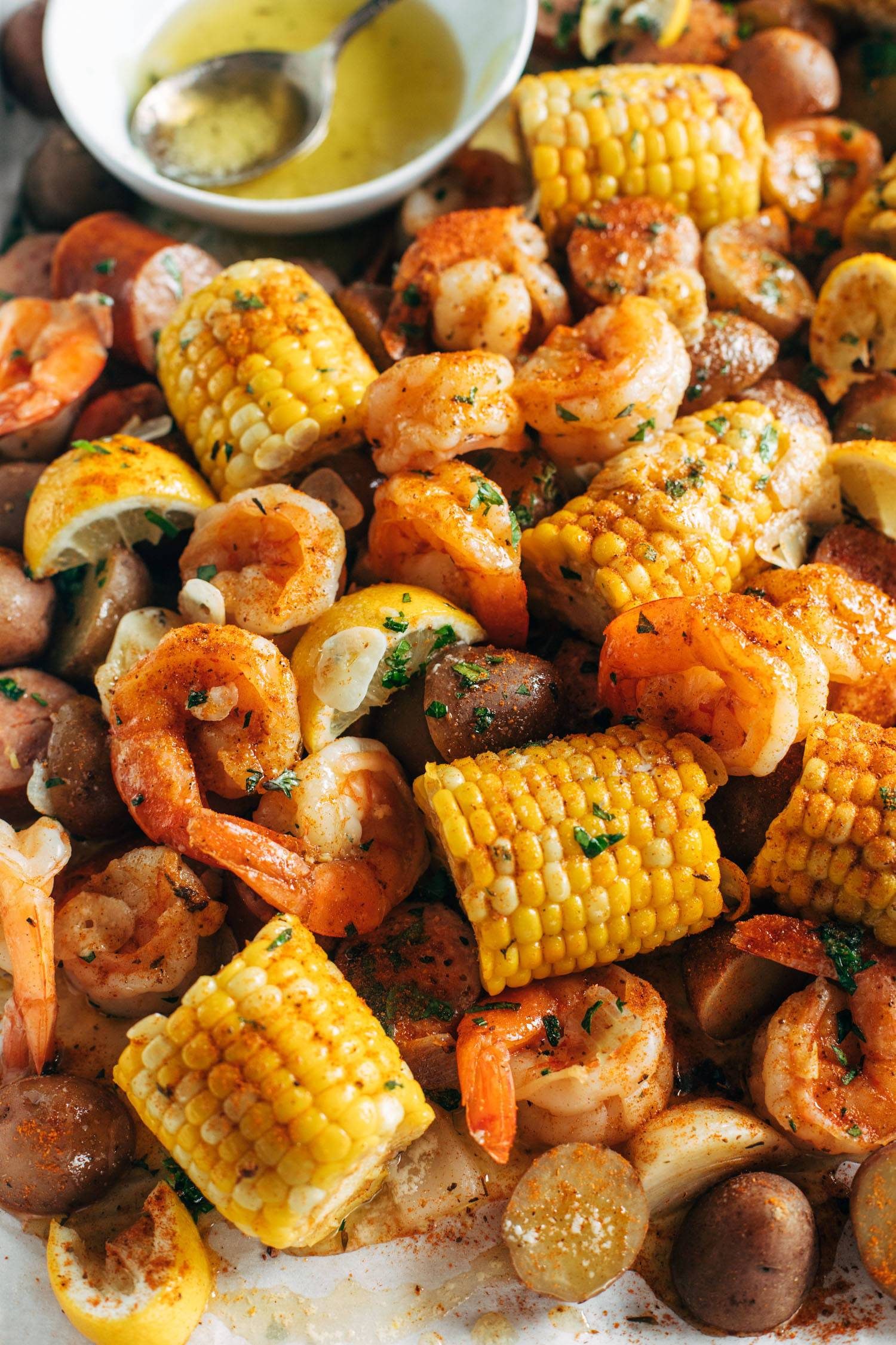 Corn, shrimp, onions, and kielbasa sausage on a platter for a shrimp boil. 